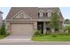 Two-story house with a brown roof, beige siding, and stone accents at 6287 Woodhaven Village Dr, Port Orange, FL 32128
