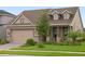 Tan two-story house with brown roof, stone accents, and a two-car garage at 6287 Woodhaven Village Dr, Port Orange, FL 32128