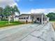 Single-wide manufactured home with covered carport and landscaped yard at 824 Silver Oak Ave, The Villages, FL 32159