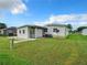 White mobile home with covered patio, lattice screen, and grassy yard at 824 Silver Oak Ave, The Villages, FL 32159