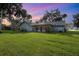 Large backyard with home, grassy lawn, and palm trees at sunset at 573 Pelican Bay Dr, Daytona Beach, FL 32119