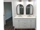 Modern bathroom with double vanity, arched mirrors, and dark tile shower at 417 S Hill Ave, Deland, FL 32724