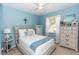 Light blue bedroom with a comfortable bed, dresser, and large window at 399 Foxhill Dr, Debary, FL 32713