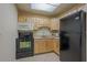 Compact kitchen featuring light wood cabinets, black appliances, and tile flooring at 1415 Ocean Shore Blvd # 303, Ormond Beach, FL 32176