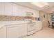 Efficient kitchen with white cabinets, tile backsplash, and appliances at 4 Oceans West Blvd # 407B, Daytona Beach Shores, FL 32118