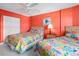 Bedroom with two double beds, orange walls, and colorful bedding at 1415 Ocean Shore Blvd # 303, Ormond Beach, FL 32176