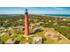 Aerial view of lighthouse, surrounding buildings, and coastline at 4650 Links Village Dr # C303, Ponce Inlet, FL 32127