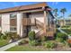 Tan condo building with brown accents, wooden stairs, and well-manicured landscaping at 600 N Boundary Ave # 106D, Deland, FL 32720