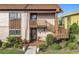 Tan condo building with brown accents, wooden stairs, and well-manicured landscaping at 600 N Boundary Ave # 106D, Deland, FL 32720