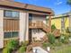 Tan condo building with brown accents, wooden stairs, and well-manicured landscaping at 600 N Boundary Ave # 106D, Deland, FL 32720