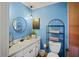 Small bathroom with blue walls, white vanity, and a metal shelving unit at 1639 Templewood Ave, Deltona, FL 32725