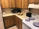 Corner kitchen with wood cabinets, stove, microwave, and appliances at 150 Wax Myrtle Woods Ct # 9D, Deltona, FL 32725