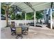 Covered patio with a dining table, grill, and surrounding landscaping at 1146 Riverside Dr, Daytona Beach, FL 32117