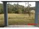View of the backyard from the covered patio, featuring a grassy lawn and surrounding trees at 2301 9Th Ave, Deland, FL 32724