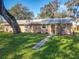 Tan brick ranch home with a brown door and landscaped yard at 2129 Lime Tree Dr, Edgewater, FL 32141