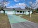 Ranch-style home with a green exterior, attached garage, and a long driveway at 525 E Roberts St, Orange City, FL 32763