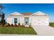 Single-story home with white exterior, teal door, and two-car garage at 1235 Tank Trl, Haines City, FL 33844