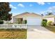 Tan house with white picket fence, attached garage, and landscaped yard at 1052 Ridgeville Rd, The Villages, FL 32162
