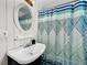 Clean bathroom with pedestal sink, patterned shower curtain, and white wainscoting at 104 Sunset Way, Fruitland Park, FL 34731