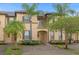 Front view of townhome with palm trees and brick driveway at 216 Calabria Ave, Davenport, FL 33897