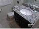Bathroom with a toilet, dark vanity, and granite countertops at 5537 Misty Oak Cir, Davenport, FL 33837