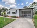 Single-story manufactured home with screened porch and lawn at 1550 Hillcrest Dr, The Villages, FL 32159