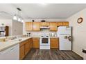 Kitchen with light wood cabinets, white appliances, and wood-look floors at 16938 Se 94Th Sunnybrook Cir, The Villages, FL 32162