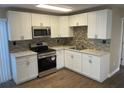 Modern kitchen featuring white shaker cabinets, stainless steel appliances, and updated backsplash at 7204 Peyton Pl, Orlando, FL 32818