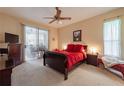 Bedroom with red bedding, ceiling fan, and access to a patio at 1900 Cherokee Hammock, Deland, FL 32720