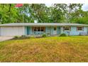 Light blue house with white garage doors and a green lawn at 6269 Se 125Th Pl, Belleview, FL 34420