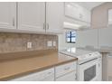 Well-equipped kitchen with white cabinets and tile backsplash at 1415 Ocean Shore Blvd # 1112, Ormond Beach, FL 32176