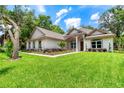 House exterior showcasing a light-colored facade, lush lawn, and mature trees at 260 Spreading Oak Ln, Ormond Beach, FL 32174