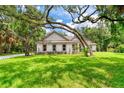 House exterior showcasing a light-colored facade, lush lawn, and mature trees at 260 Spreading Oak Ln, Ormond Beach, FL 32174