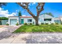 Single story home with light blue exterior, a brick driveway and a large oak tree at 309 Sears Ave, Daytona Beach, FL 32118