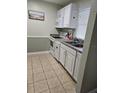 Efficient kitchen with white cabinets, tiled floors, and modern appliances at 1510 Ocean Shore Blvd # 4140, Ormond Beach, FL 32176
