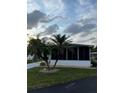Single-wide mobile home with screened porch and palm trees at 216 Rue De Paresse, Tavares, FL 32778