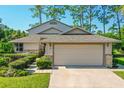 Tan house with a two-car garage and well-manicured landscaping at 7 Jasmine Run, Ormond Beach, FL 32174