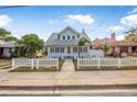 Light blue beach house with white picket fence and lush landscaping under a bright sky at 318 Vermont Ave, Daytona Beach, FL 32118