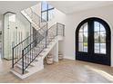 Elegant entryway with grand staircase, arched doorway, and wine storage at 16340 Pendio Dr, Bella Collina, FL 34756