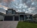 Two-story house with gray exterior and three car garage at 2099 Keystone Pass Blvd, Minneola, FL 34715