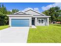 Newly built home with a blue garage door and landscaped yard at 30 Malauka Run Ln, Ocklawaha, FL 32179