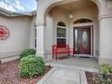 Inviting front porch with red bench, arched entryway and landscaping at 1751 Ashwood Run, The Villages, FL 32162