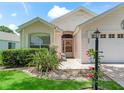 House exterior featuring a light-colored facade, entryway, and landscaping at 1405 W Schwartz Blvd, The Villages, FL 32159