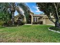 Tan house exterior with lush landscaping and palm trees at 13144 Coldwater Loop, Clermont, FL 34711