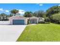House exterior showcasing a teal garage door and lush landscaping at 12270 Virginia Dr, Leesburg, FL 34788