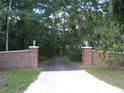 Brick pillars and lush landscaping frame the private driveway entrance at 415 Se 123Rd Street Rd, Ocala, FL 34480