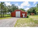 Red metal barn with a large roll-up door and additional storage building at 13910 Max Hooks Rd, Clermont, FL 34711