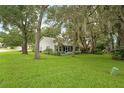 House nestled in a lush green backyard with large trees at 131 Costa Mesa Dr, The Villages, FL 32159