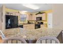 Bright kitchen with granite countertops and black appliances at 8084 Se 175Th Malmaison St, The Villages, FL 32162