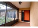 Inviting front porch with an orange door and screened enclosure at 14700 Se 94Th Ave, Summerfield, FL 34491